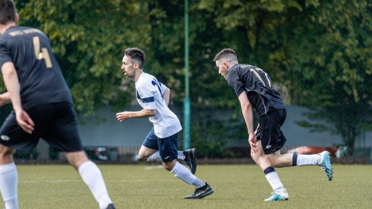 Daniel Silva of Krakow Dragoons FC running between two Wawel opponents