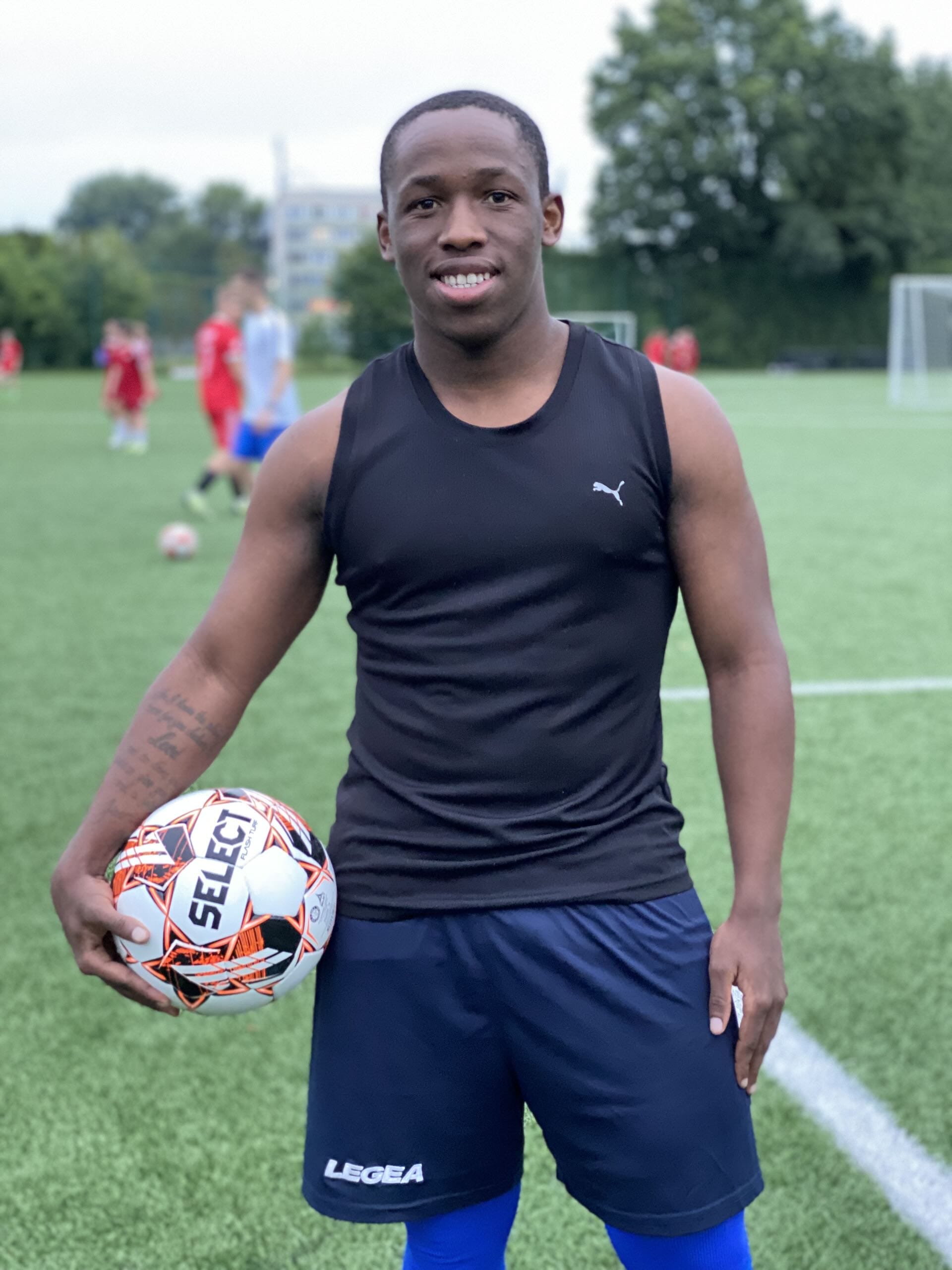Keanu Solomons of Krakow Dragoons FC smiling while posing for a photo holding a football during a training