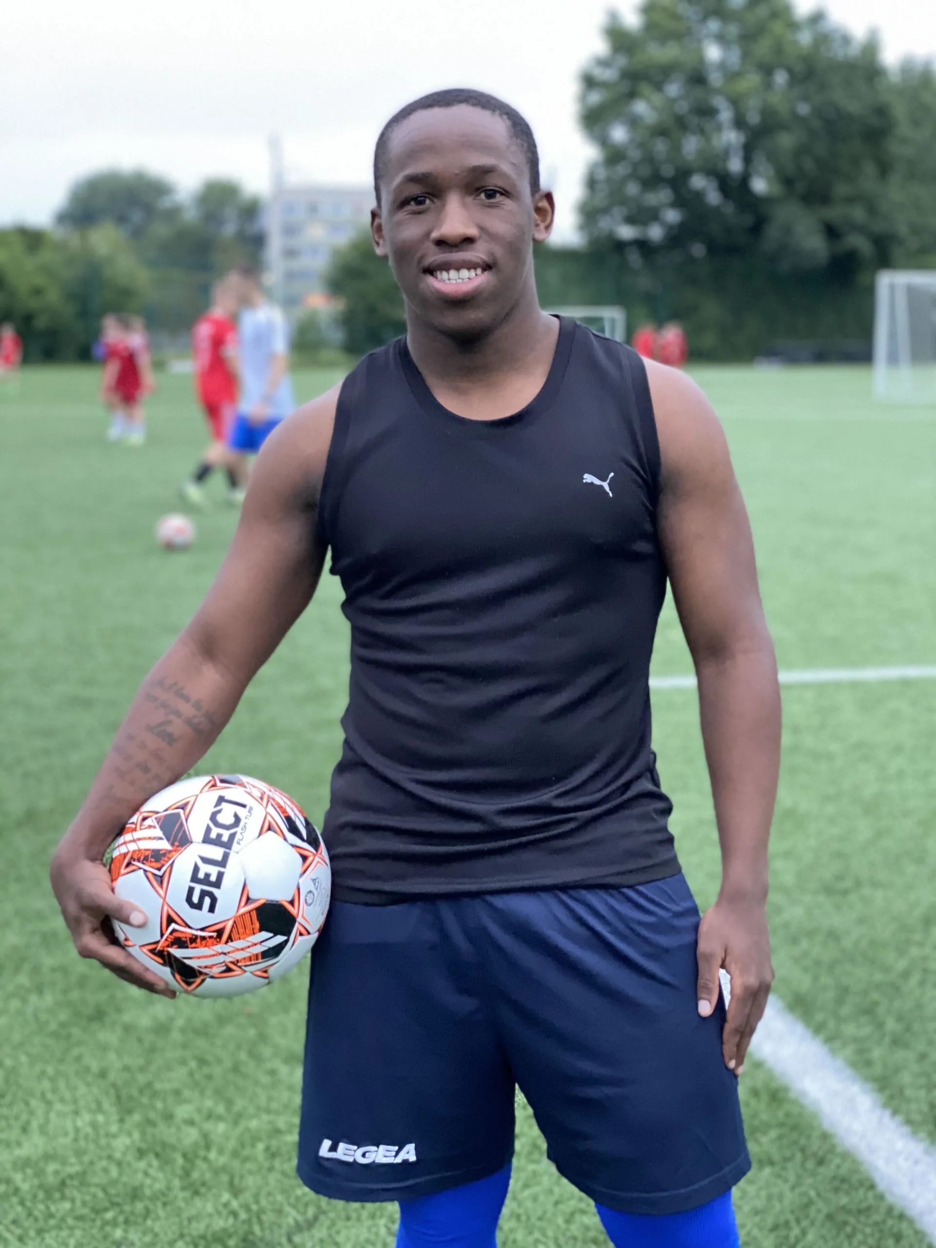Keanu Solomons of Krakow Dragoons FC smiling while posing for a photo holding a football during a training