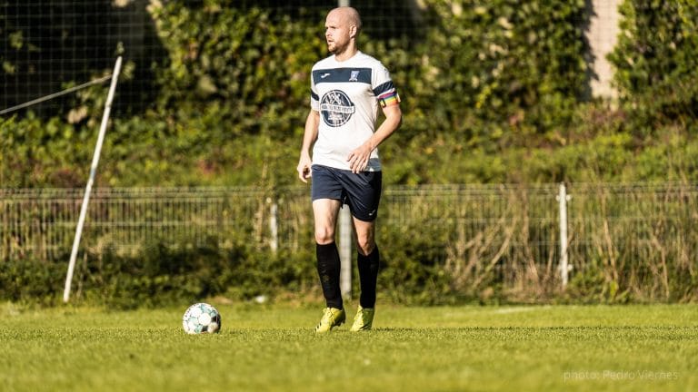 Alexey Zelenkin of Krakow Dragoons FC controlling the ball during a match in a football field surrounded by greenery