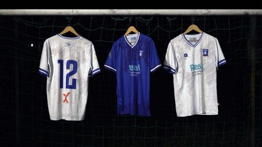 Three hangers on a goal showcase the new Krakow Dragoons FC 2022/23 kits: two away jerseys in white and one home jersey in blue