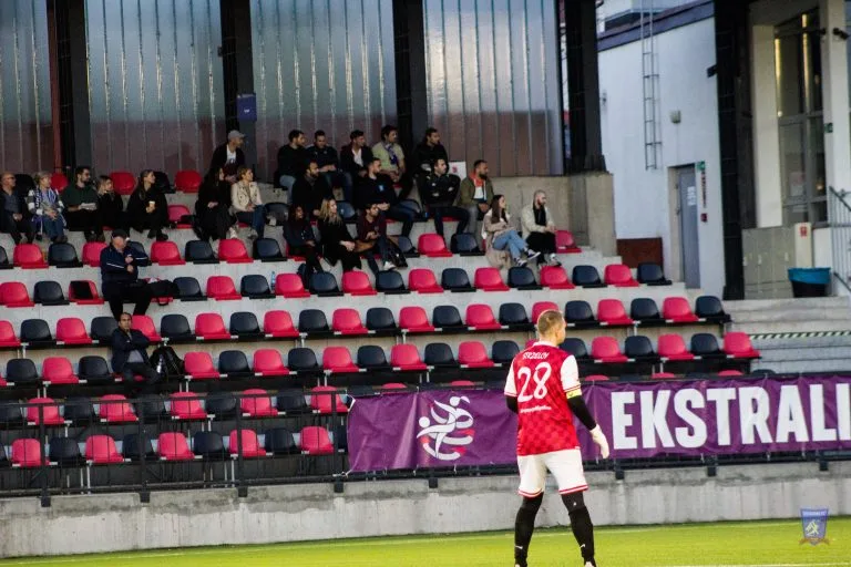 Strzelcy goalkeeper Rafał Juszczyk and football fans at the stands vs Krakow Dragoons FC