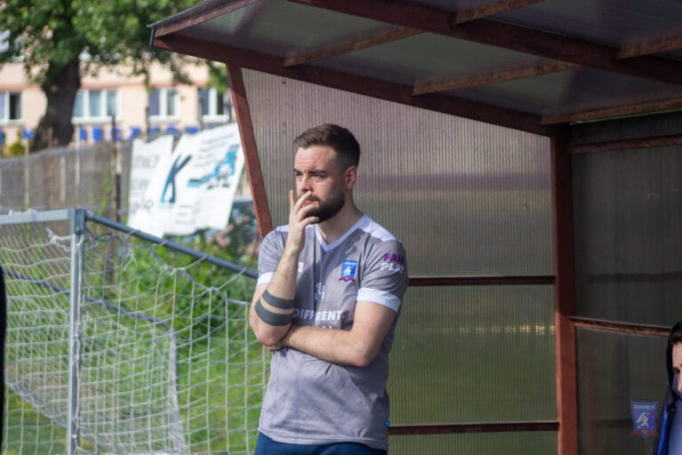 Michael Syska-Lamb pensative as he watches a match from the sideline