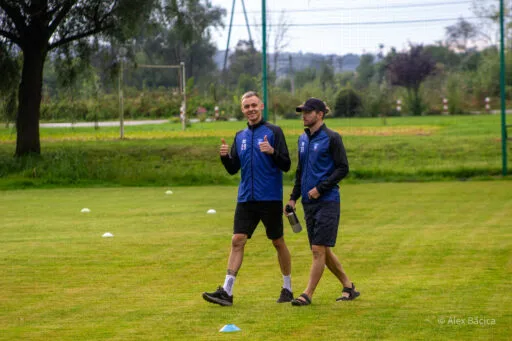 Players of Krakow Dragoons FC walking on the pitch and giving thumbs up to the photographer