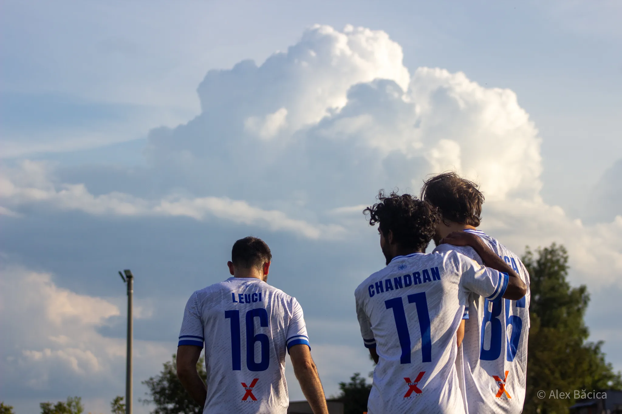 Players of Krakow Dragoons FC celebrating a goal with a nice view of a corn field and a dramatic sky in the background