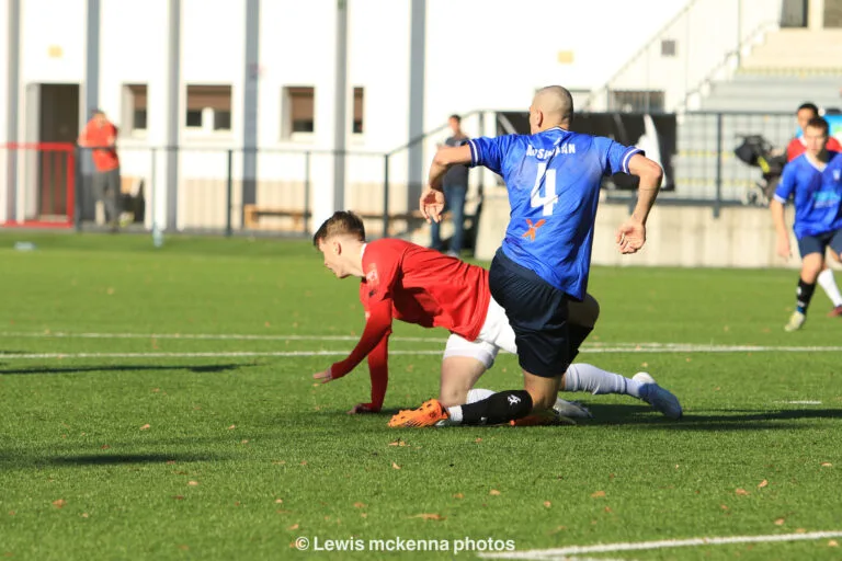 Sasha Arshakian of Krakow Dragoons FC and a FC United of Manchester opponent, stand from the ground after a disputed ball