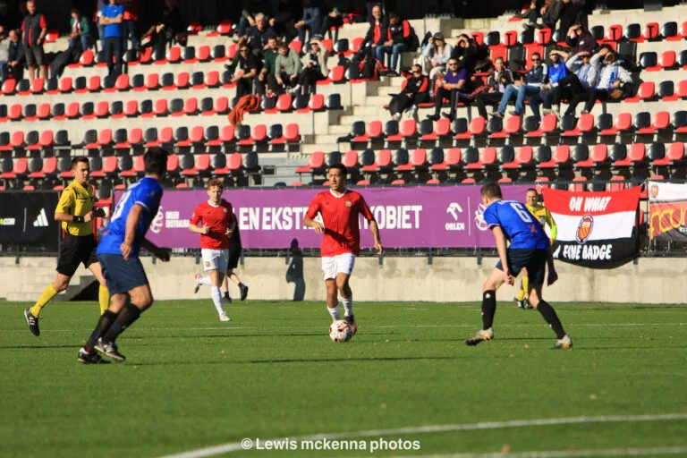 A FC United of Manchester player carries the ball forward into the Krakow Dragoons FC half