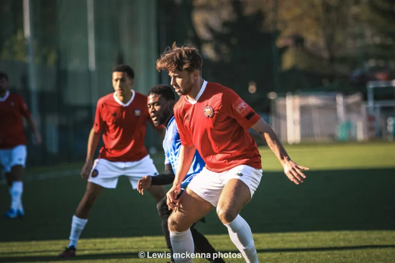 Corneille Malonga of Krakow Dragoons FC and a FC United of Manchester player ready to dispute an incoming pass