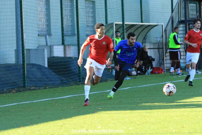 A FC United of Manchester player carries the ball forward leaving behind Salah Missi of Krakow Dragoons FC