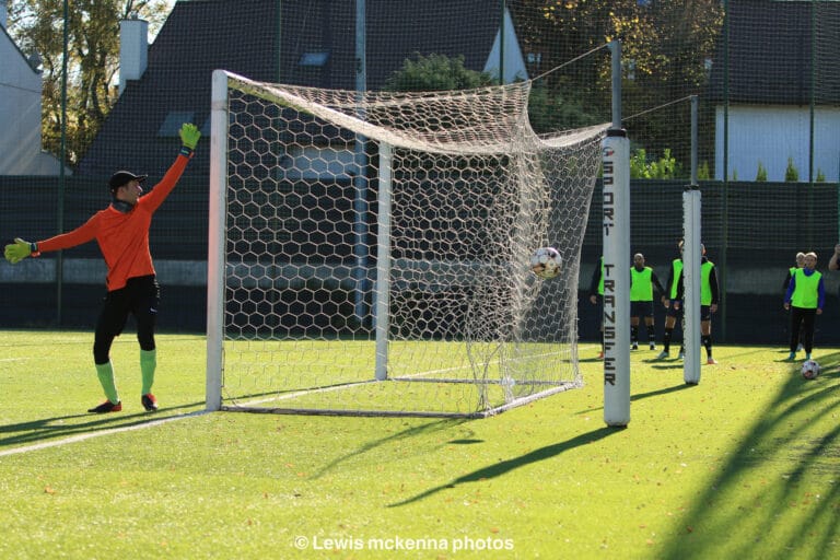 Marcin Obyrtacz and Krakow Dragoons FC subs watch as a ball from the opponents hits the side net of the goal