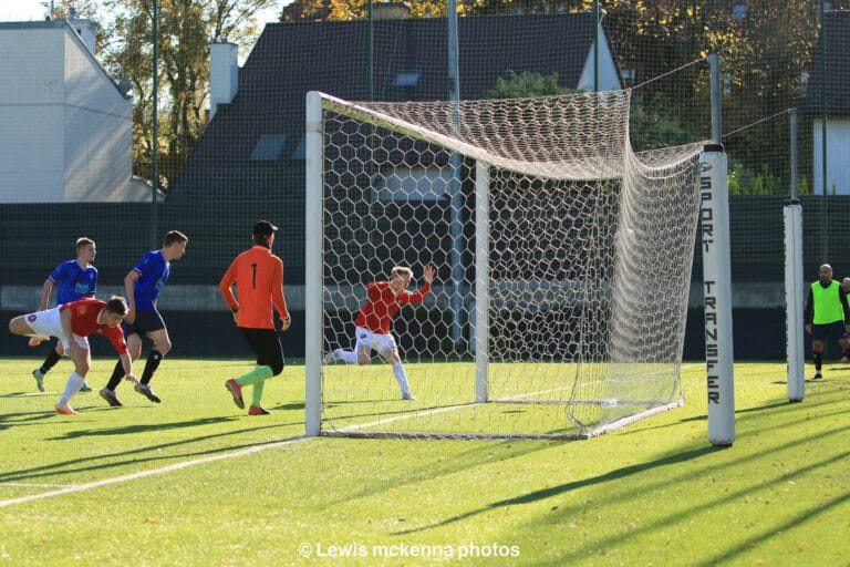 Two players of FC United of Manchester try to reach an aerial ball inside the Krakow Dragoons FC box