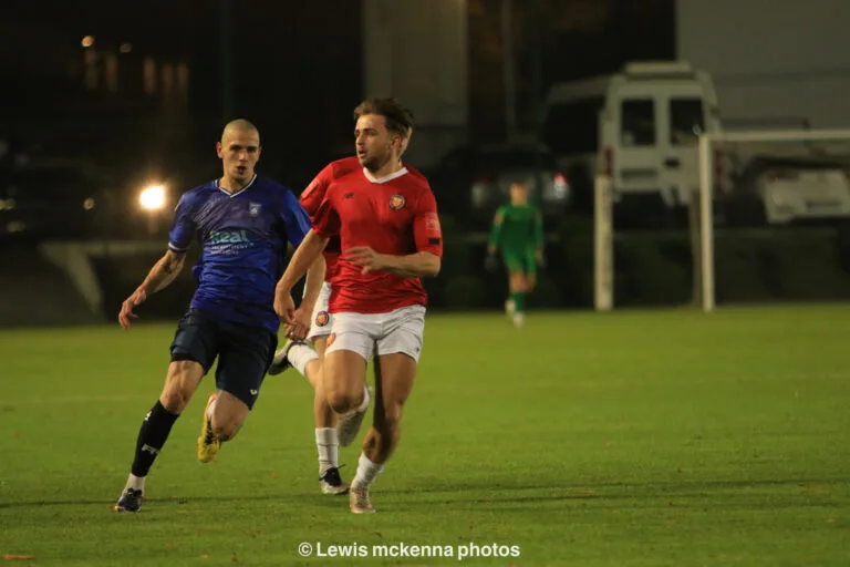 A FC United of Manchester player and Sasha Arshakian of Krakow Dragoons FC run forward ready to dispute a ball