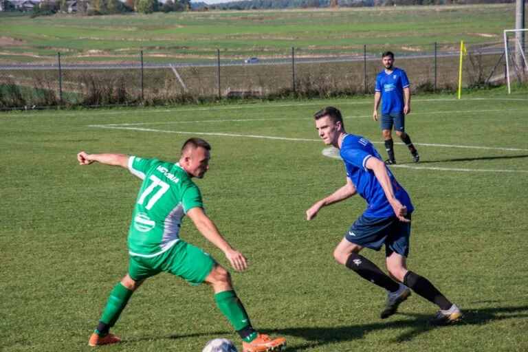 Brian Lemmen of Krakow Dragoons FC disputes a ball with a Victoria Smroków opponent