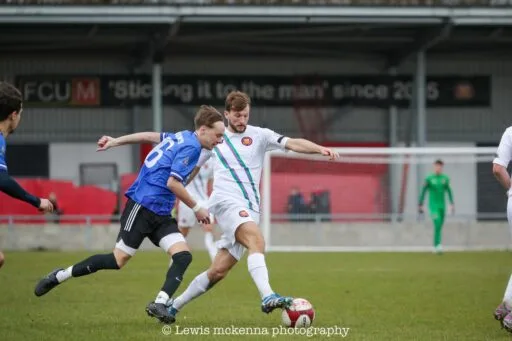 Jan Krzyzanowski of Krakow Dragoons FC disputes a ball against a FC United of Manchester player