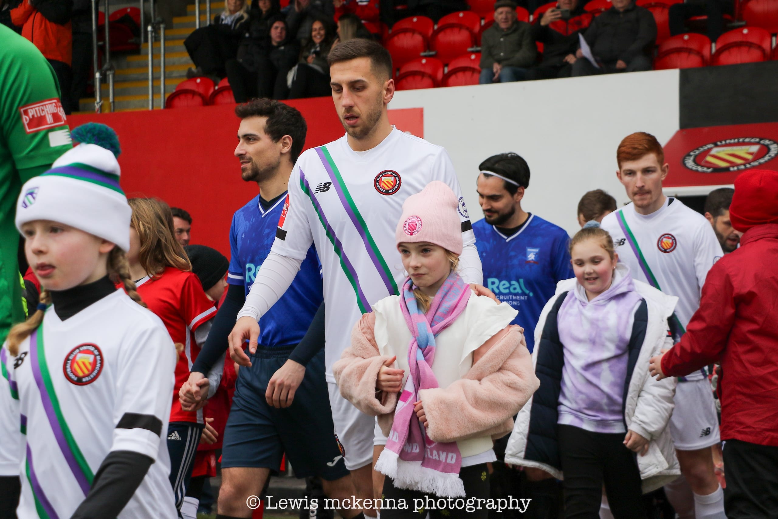 FC United of Manchester and Krakow Dragoons FC players entering the pitch with mascot children