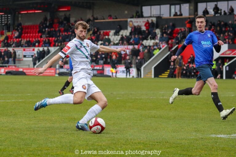 A FC United of Manchester player shooting at goal