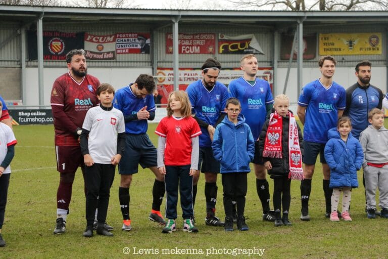 Players of Krakow Dragoons FC posing with children wearing Poland jerseys and scarves before match