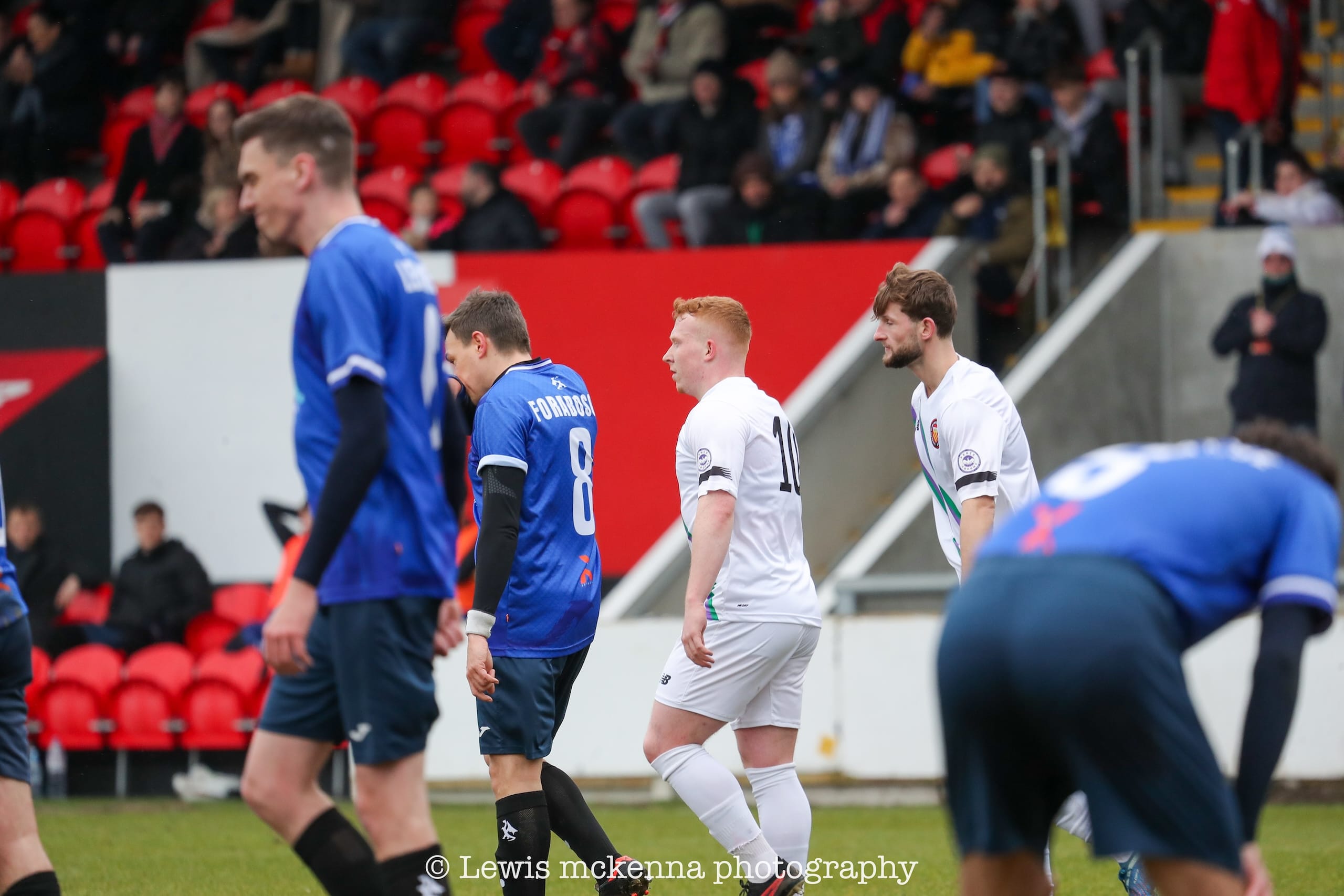 Players of FC United of Manchester and Krakow Dragoons FC with contrasting spirits after the home team scores a goal