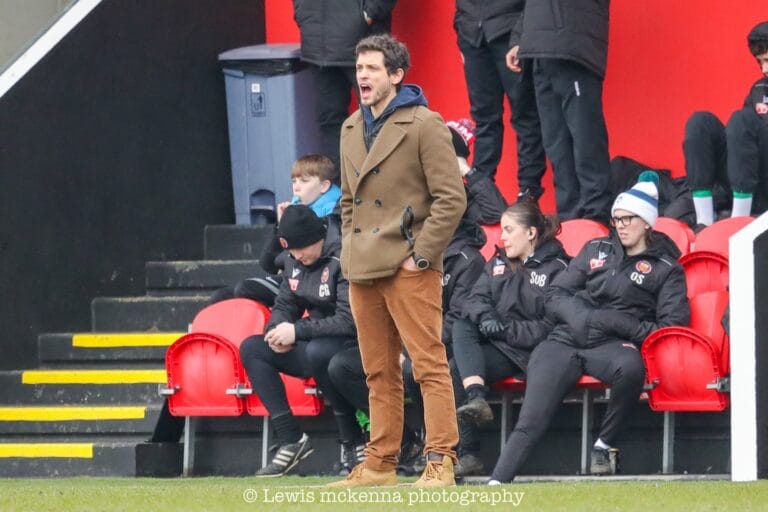 Krakow Dragoons FC head coach Hugo Cruz giving instructions from the dugout to his players during a match vs FC United of Manchester