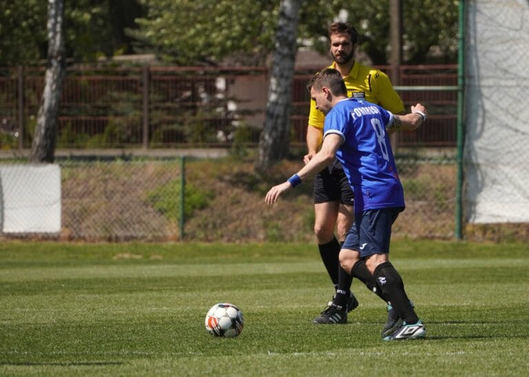 Enrico Forabosco of Krakow Dragoons FC preparing a pass with the referee in the background