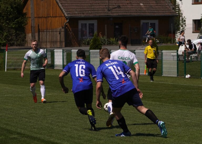 Galicja Raciborowice players carrying the ball forward with two Krakow Dragoons FC players nearby