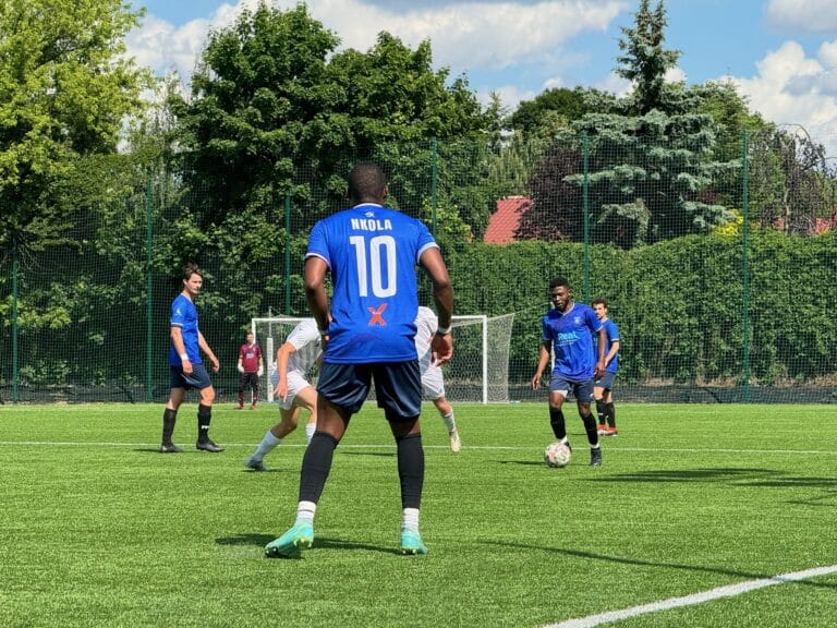 Corneille Malonga of Krakow Dragoons FC carrying the ball forward while Flavio Nkola waits for the pass