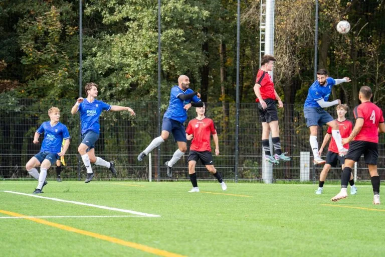 An aerial ball with multiple players of Krakow Dragoons FC and Sportowiec Modlniczka jumping in the air