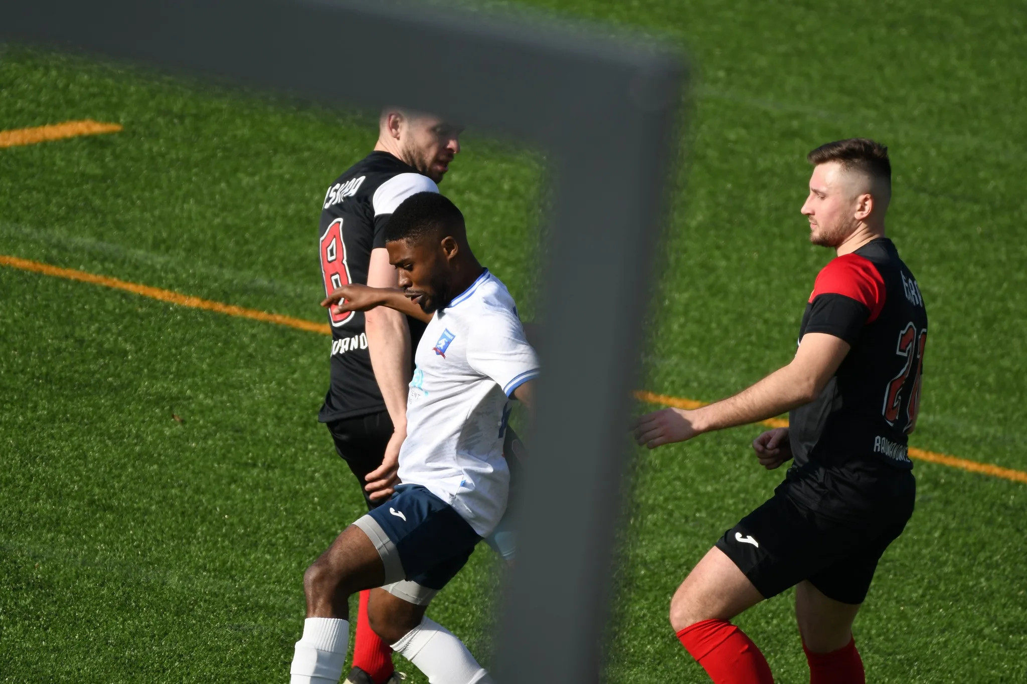 Corneille Malonga of Krakow Dragoons FC dominating the ball between two Iskra Radwanowice opponents