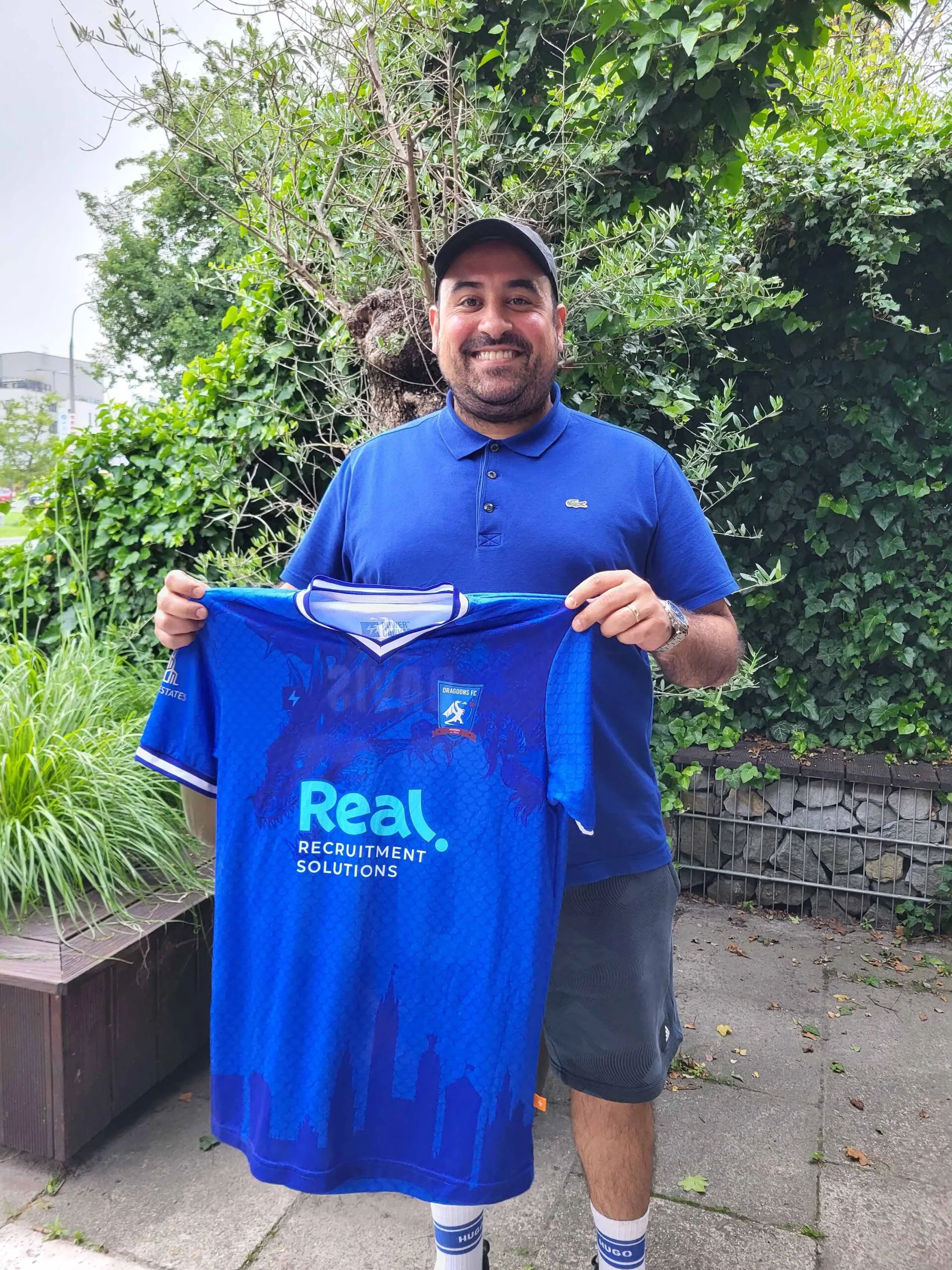 Gonçalo Ferreira, the new Krakow Dragoons FC Head Coach, smiling as he holds a Dragoons jersey to the camera