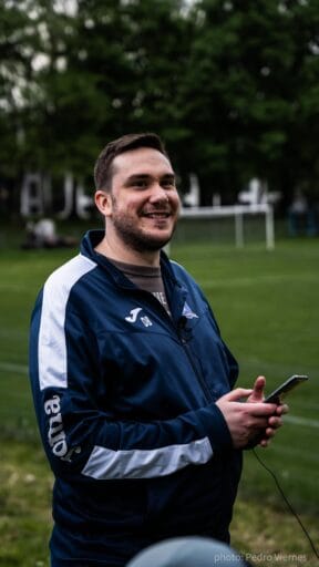 Dave Burch of Krakow Dragoons FC smiling to someone as he's using his phone