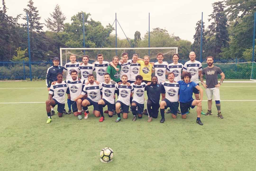 Krakow Dragoons FC players posing for a photo in front a football goal after a friendly match in Warsaw