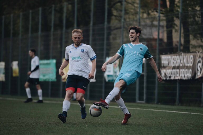 A Prague Raptors player controls the ball with Szymon Urzędowski of Krakow Dragoons FC closing in
